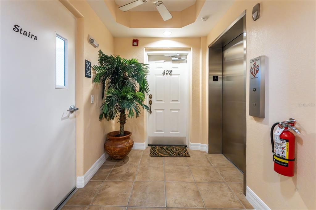 A hallway features a door labeled 402, an elevator, a potted plant, and a fire extinguisher — 2225 N BEACH ROAD UNIT 402, ENGLEWOOD, FL