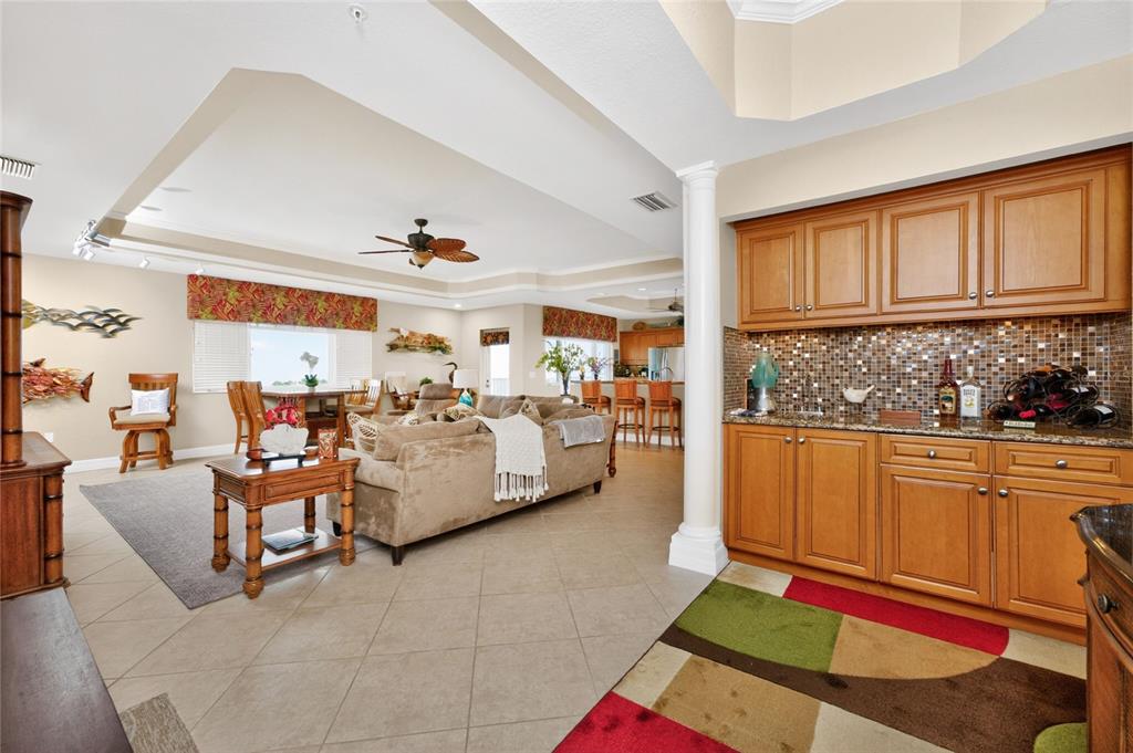 A living room with a wet bar, tile flooring, and a tray ceiling — 2225 N BEACH ROAD UNIT 402, ENGLEWOOD, FL
