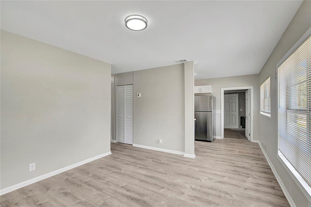 A living area with light wood-look flooring leads to a kitchen with stainless steel appliances — 7015 FILBERT LANE, TAMPA, FL