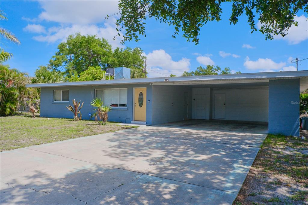 A blue single-story house with a carport sits behind a large tree in a yard — 993 GARY STREET UNIT A & B, SARASOTA, FL