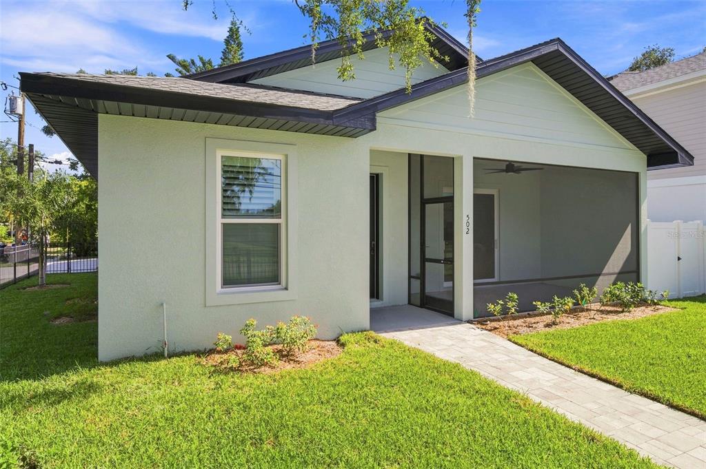 A light green house with a dark roof and a screened-in front porch — 502 BELTREES STREET, DUNEDIN, FL