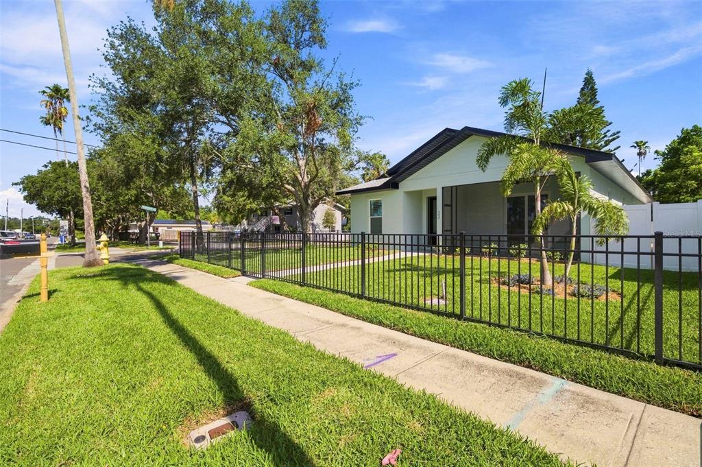 A single-story house with a white exterior and a black metal fence in the front yard — 502 BELTREES STREET, DUNEDIN, FL