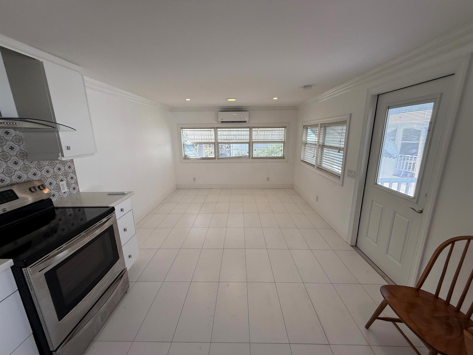 A kitchen with white cabinets, stainless steel appliances, tiled floors, and a glass-paned exterior door — 206 Eagle Drive E, Briny Breezes FL 33435, BRINY BREEZES, FL