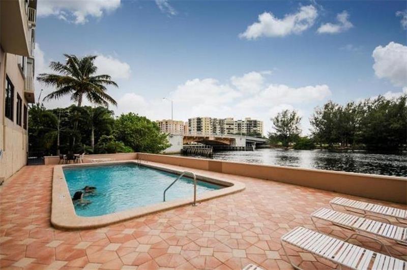 A swimming pool on a tiled patio overlooks a river and a bridge — 1401 N Riverside Drive # 307, Pompano Beach FL 33062, POMPANO BEACH, FL