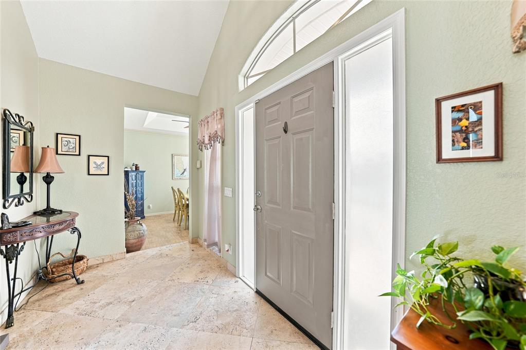 A foyer with tile flooring, a gray front door, and a view into a dining room — 5219 GUAVA TERRACE, PORT CHARLOTTE, FL