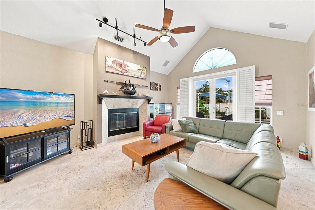 A living room features a vaulted ceiling, a fireplace, tile flooring, and a sectional sofa — 5219 GUAVA TERRACE, PORT CHARLOTTE, FL