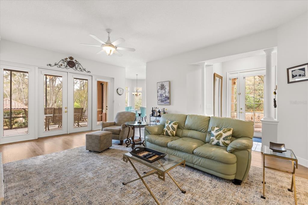 A living room features a green leather sofa, glass coffee table, and glass patio doors — 102 CAMINO REAL BOULEVARD UNIT 102, HOWEY IN THE HILLS, FL