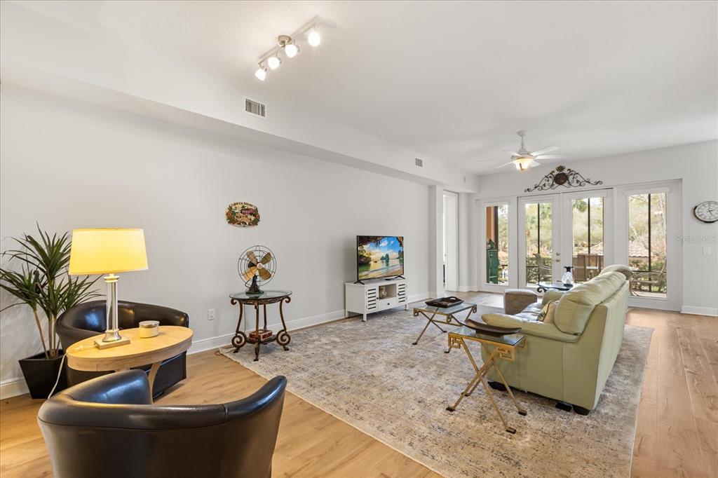 A living room features light wood flooring, a light green sofa, and glass patio doors — 102 CAMINO REAL BOULEVARD UNIT 102, HOWEY IN THE HILLS, FL