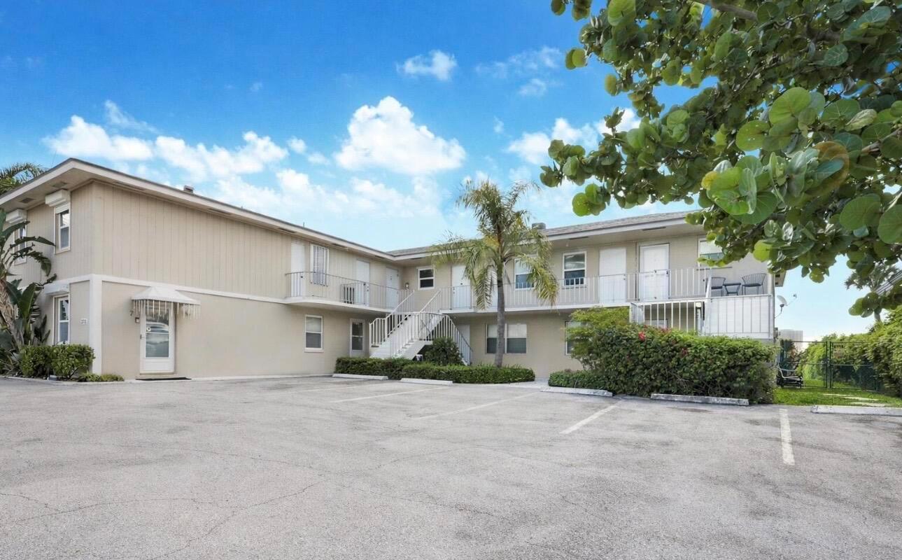 A two-story apartment building with a parking lot and exterior staircases under a blue sky — 370 Wilma Circle # 6, Riviera Beach FL 33404, RIVIERA BEACH, FL