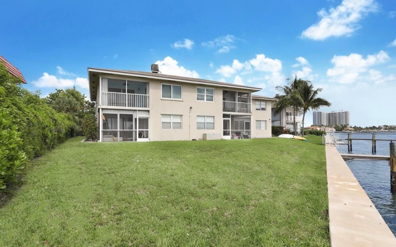 A two-story apartment building with screened balconies sits on a grassy lawn beside a canal — 370 Wilma Circle # 6, Riviera Beach FL 33404, RIVIERA BEACH, FL