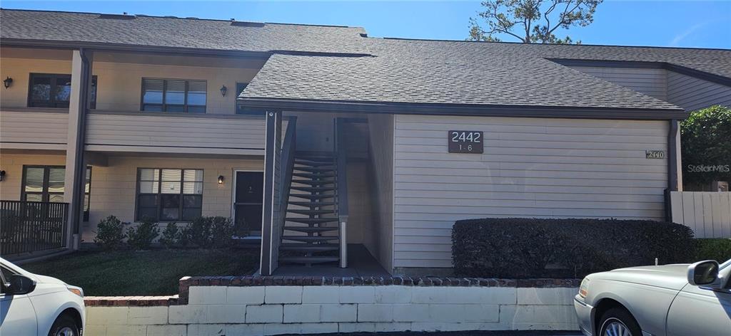 A two-story apartment building exterior features tan siding, a shingled roof, and an outdoor staircase — 2442 NE 7TH STREET UNIT 3, OCALA, FL