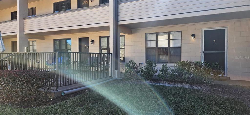 A ground-level apartment exterior features a patio with a metal railing and unit number three — 2442 NE 7TH STREET UNIT 3, OCALA, FL