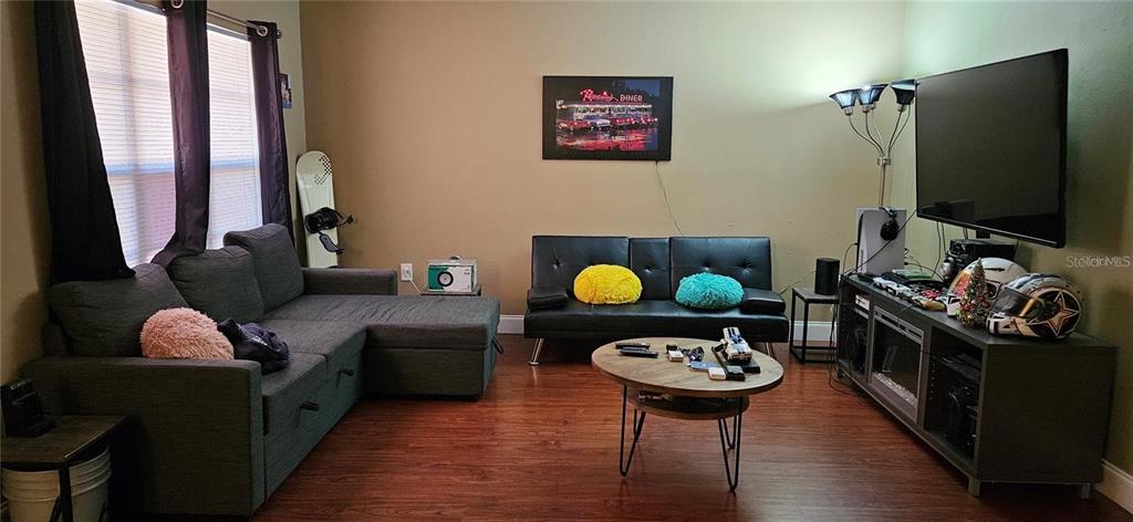 A living room features a sectional sofa, a black futon, a coffee table, and a television — 2442 NE 7TH STREET UNIT 3, OCALA, FL