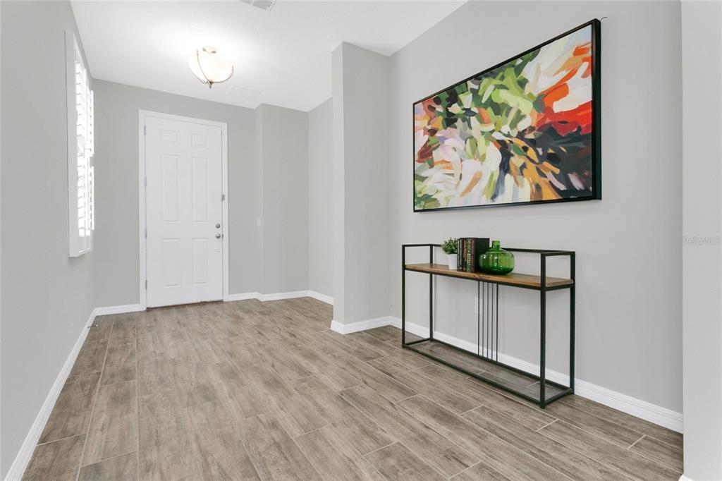 A bright entryway features gray walls, wood-look tile flooring, a console table, and abstract art — 9169 WAVERLY WALK DRIVE, ORLANDO, FL