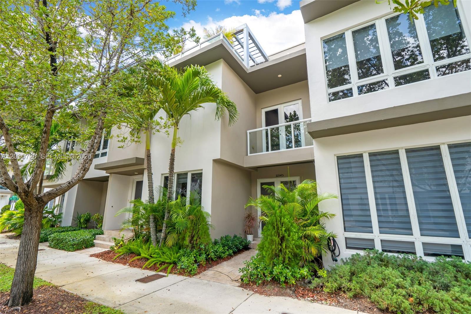 A modern two-story townhouse exterior features white walls, large windows, and a small balcony — 10545 NW 63rd Ter, Doral FL 33178, DORAL, FL