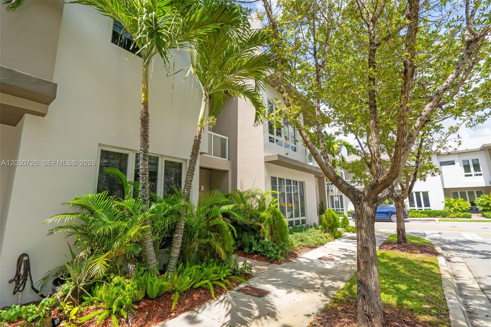The exterior of a modern multi-story residential building features palm trees and a paved walkway — 10545 NW 63rd Ter, Doral FL 33178, DORAL, FL