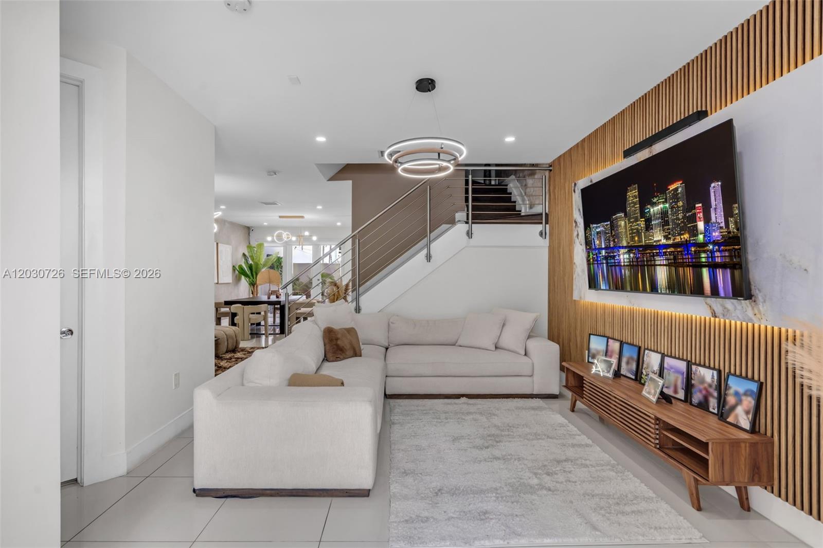A living room features a white sectional sofa, a slatted wood wall, and a television — 10545 NW 63rd Ter, Doral FL 33178, DORAL, FL