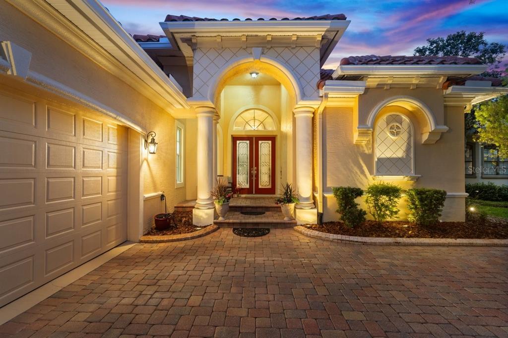 A paved driveway leads to the arched entryway and double front doors of a house — 102 LAGARE STREET, PALM COAST, FL