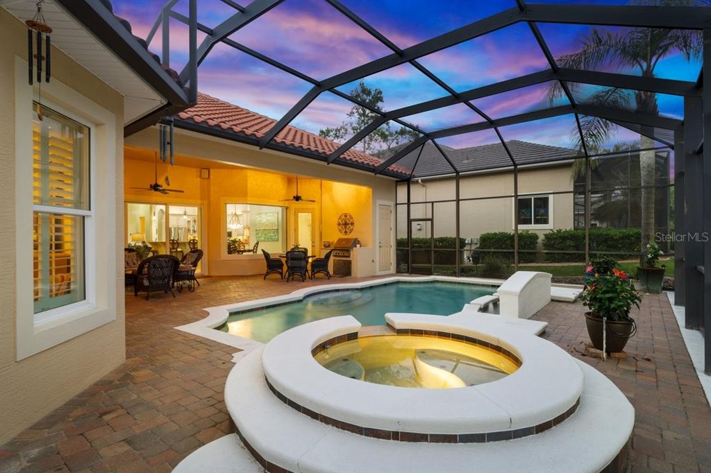 A screened-in patio features a swimming pool, a raised hot tub, and brick pavers — 102 LAGARE STREET, PALM COAST, FL