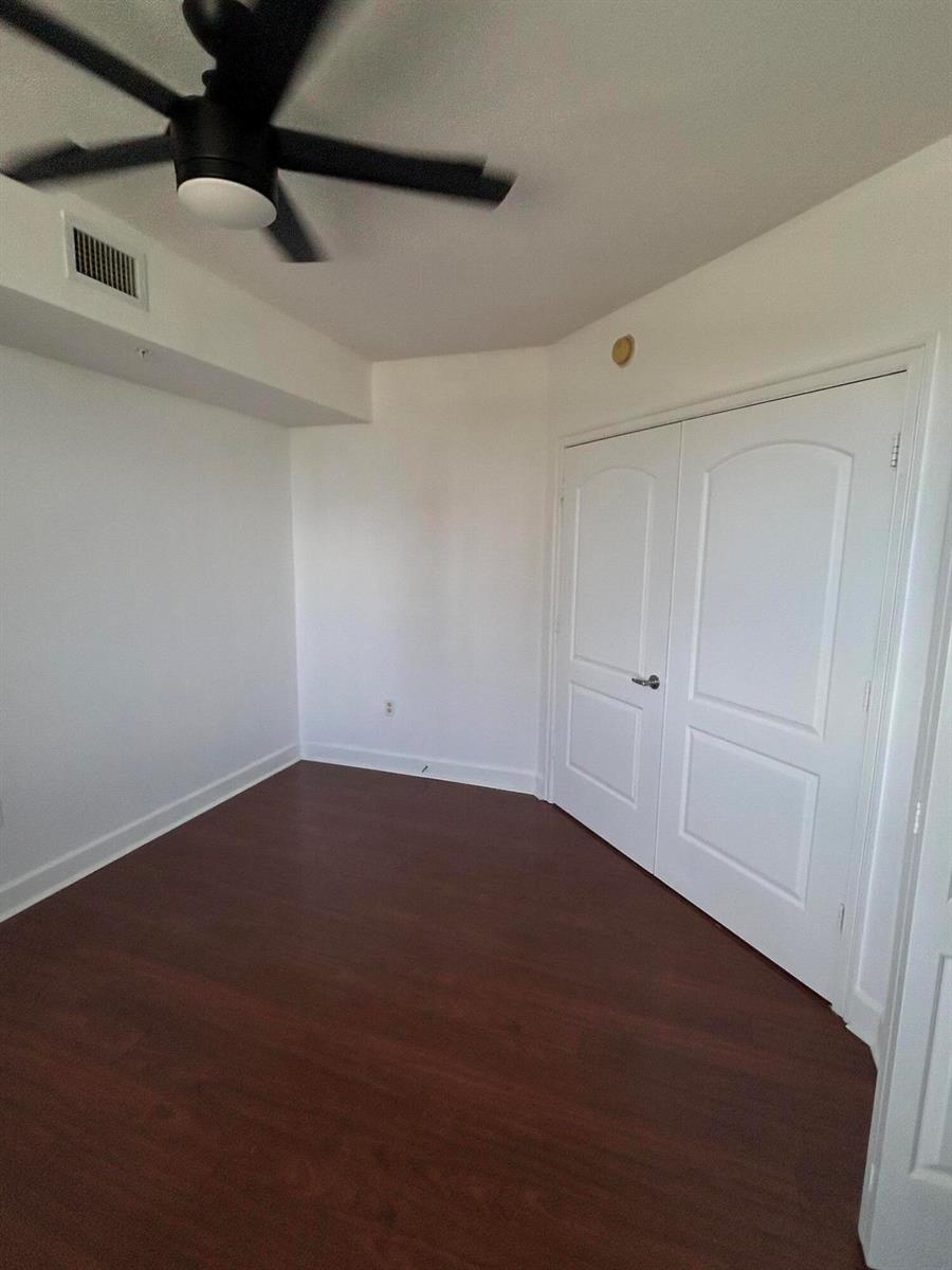 An empty room with dark wood-look flooring, a ceiling fan, and white double closet doors — 1830 Radius Drive # 514, Hollywood FL 33020, HOLLYWOOD, FL