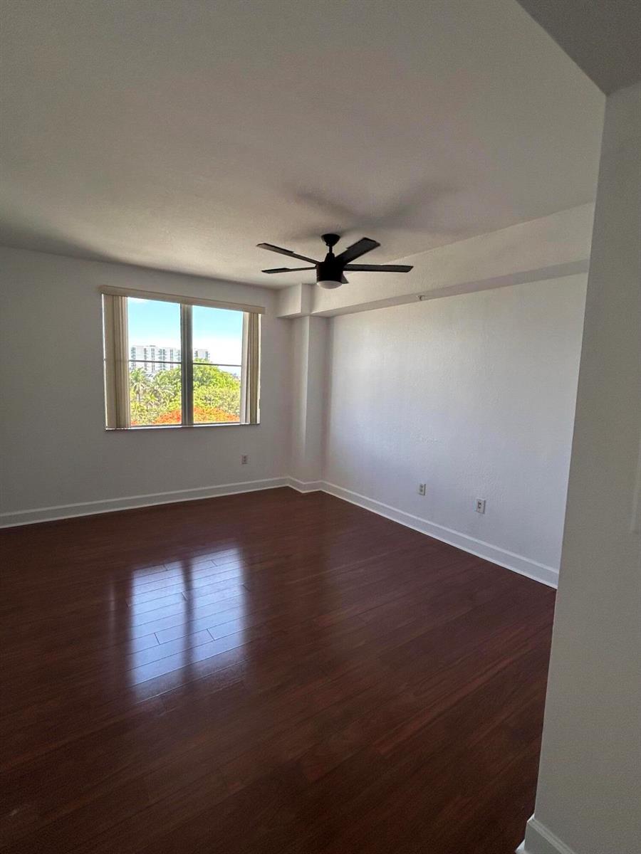 An empty room with dark wood flooring, white walls, a ceiling fan, and a window — 1830 Radius Drive # 514, Hollywood FL 33020, HOLLYWOOD, FL