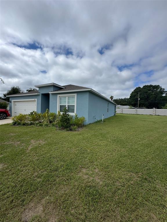A blue single-story house with a white garage door sits on a large grassy lot — 823 AUBURN GROVE COURT, AUBURNDALE, FL
