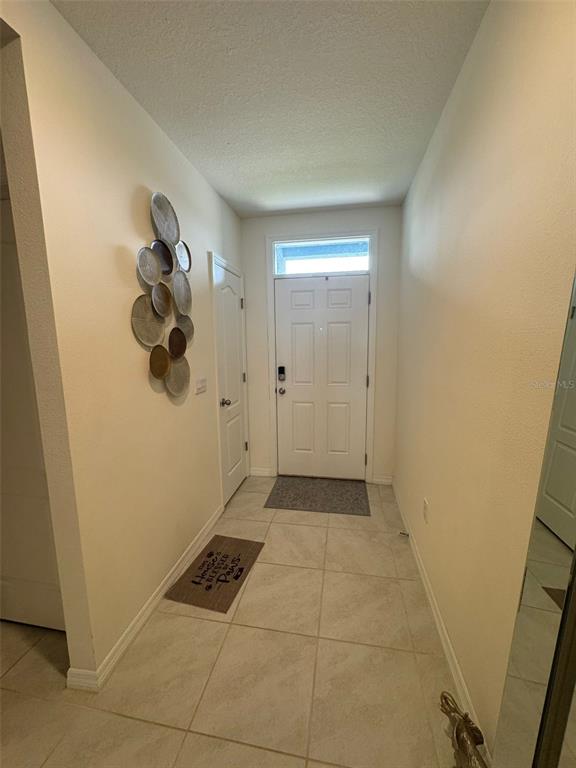 An entryway features tile flooring, a white front door, and decorative wall plates — 823 AUBURN GROVE COURT, AUBURNDALE, FL