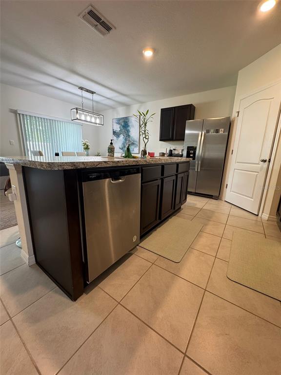 A kitchen features dark wood cabinets, stainless steel appliances, and a granite-topped island — 823 AUBURN GROVE COURT, AUBURNDALE, FL