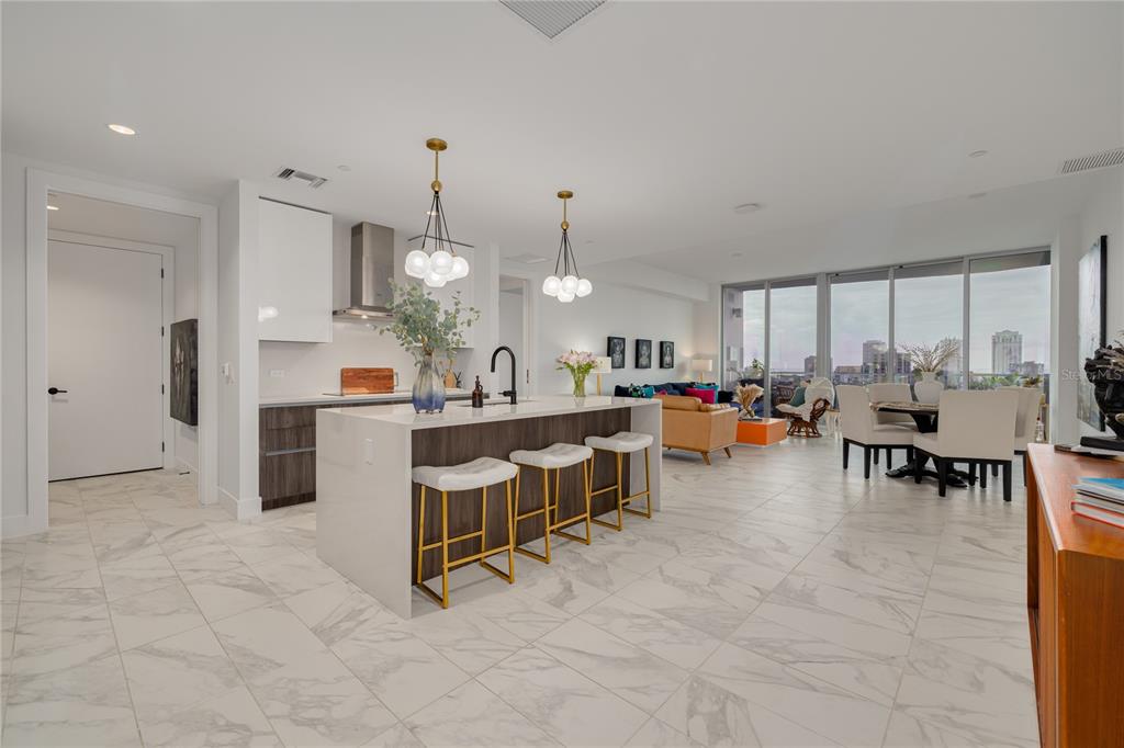 A modern kitchen with a white island and bar stools opens into a bright living area — 777 3RD AVENUE N UNIT 1104, ST PETERSBURG, FL