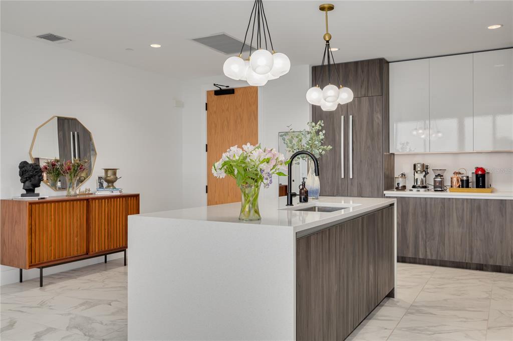 A modern kitchen features a white quartz island, dark wood cabinetry, and two globe pendant lights — 777 3RD AVENUE N UNIT 1104, ST PETERSBURG, FL