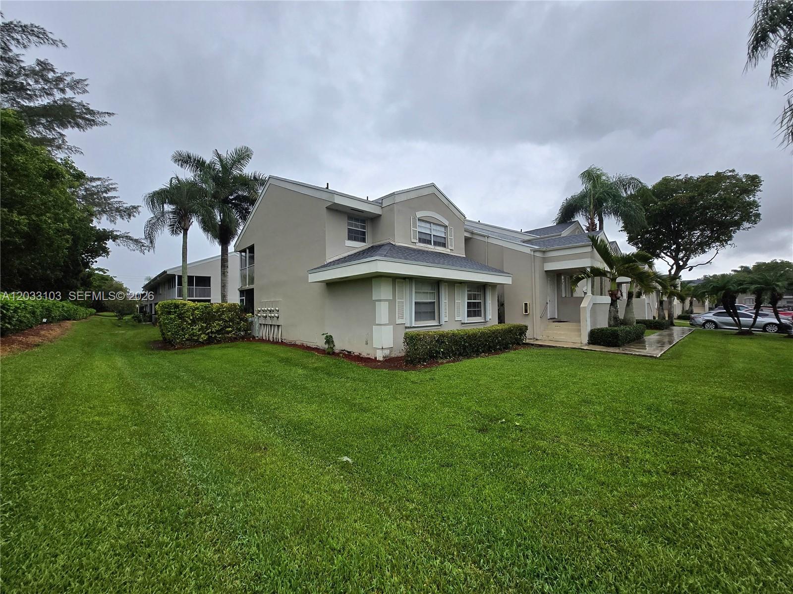 A two-story residential building with a beige exterior, dark roof, and surrounding lawn — 2629 SE 21st Ct # C, Homestead FL 33035, HOMESTEAD, FL
