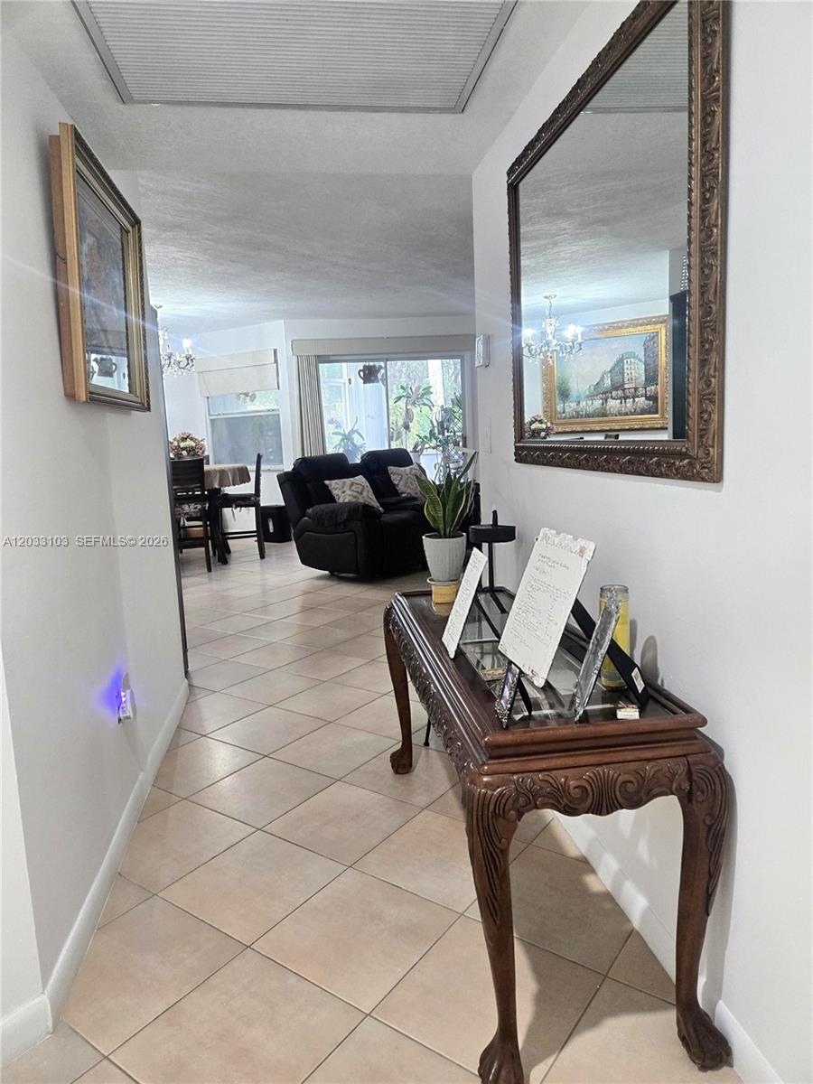 A tiled hallway leads to a living room and dining area with a wooden console — 2629 SE 21st Ct # C, Homestead FL 33035, HOMESTEAD, FL