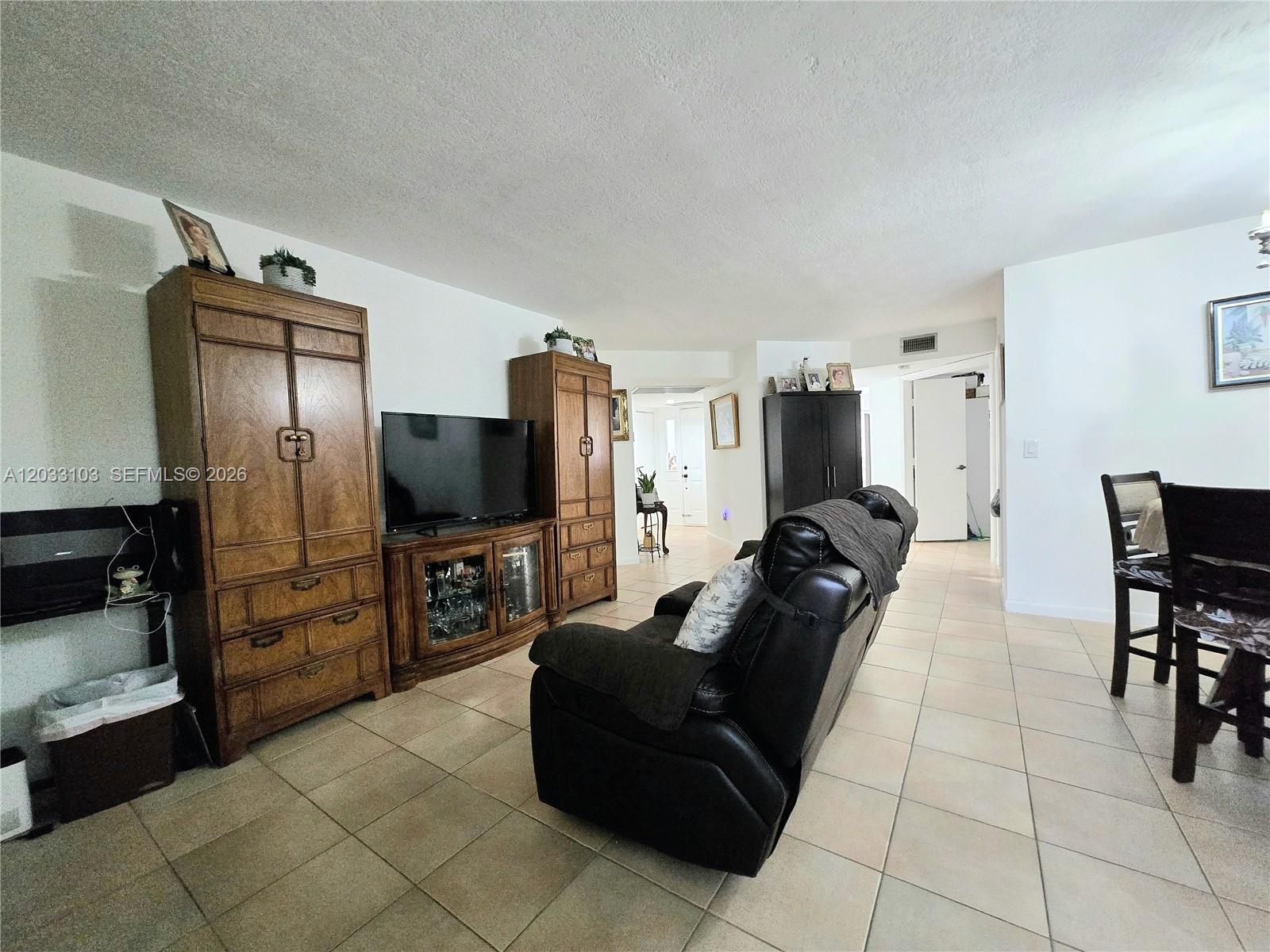 A living room features tile flooring, a large wooden entertainment center, and a leather recliner — 2629 SE 21st Ct # C, Homestead FL 33035, HOMESTEAD, FL