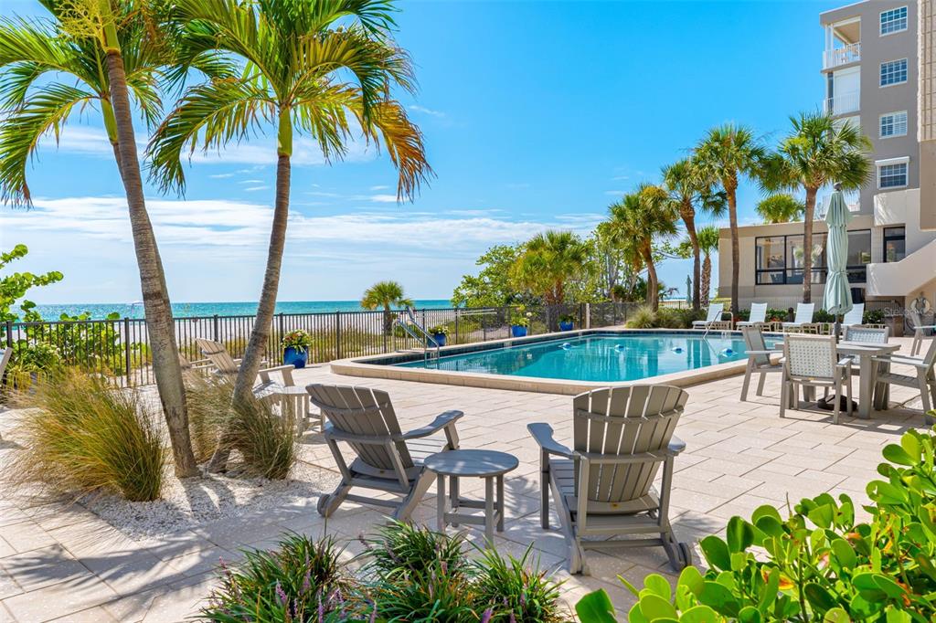 A swimming pool sits on a patio with lounge chairs overlooking the ocean and beach — 19700 GULF BOULEVARD UNIT 403, INDIAN SHORES, FL