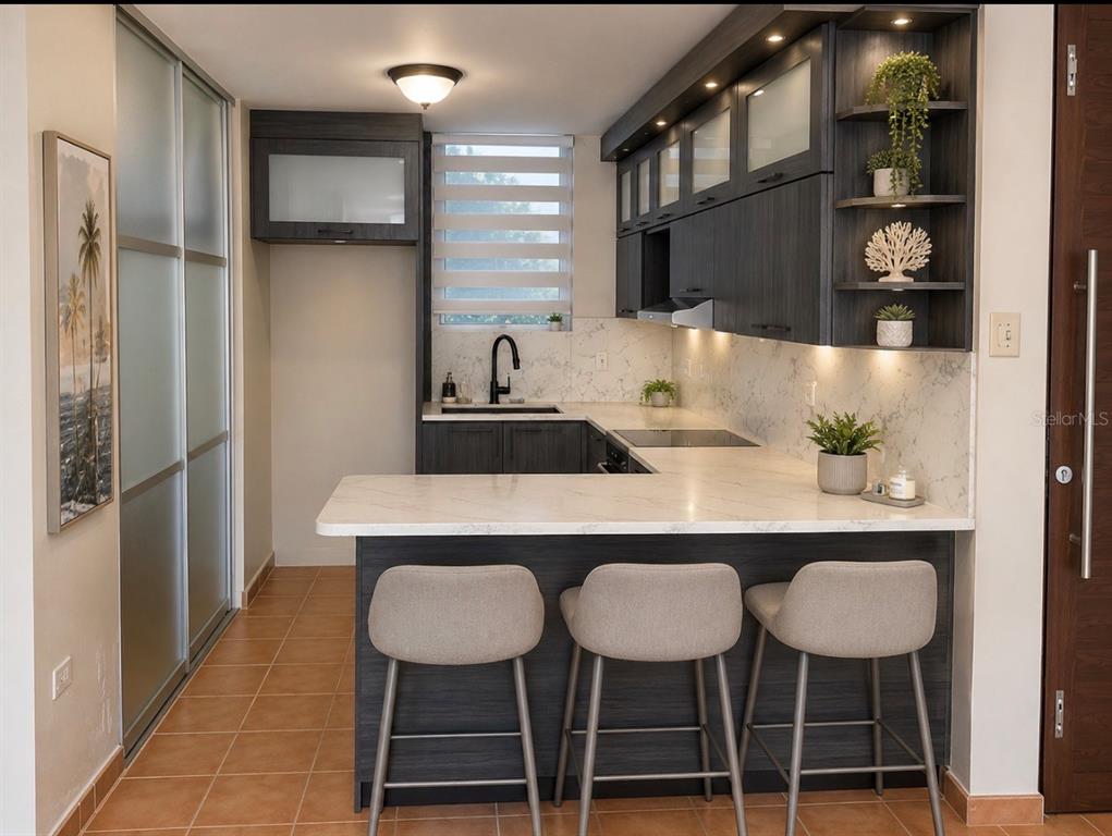 A modern kitchen features dark wood cabinetry, white marble countertops, and three bar stools — 5015 PUNTA TUNA UNIT 401, MAUNABO, PR