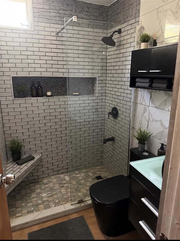 A modern bathroom features a glass-enclosed shower with gray subway tile and a black toilet — 5015 PUNTA TUNA UNIT 401, MAUNABO, PR