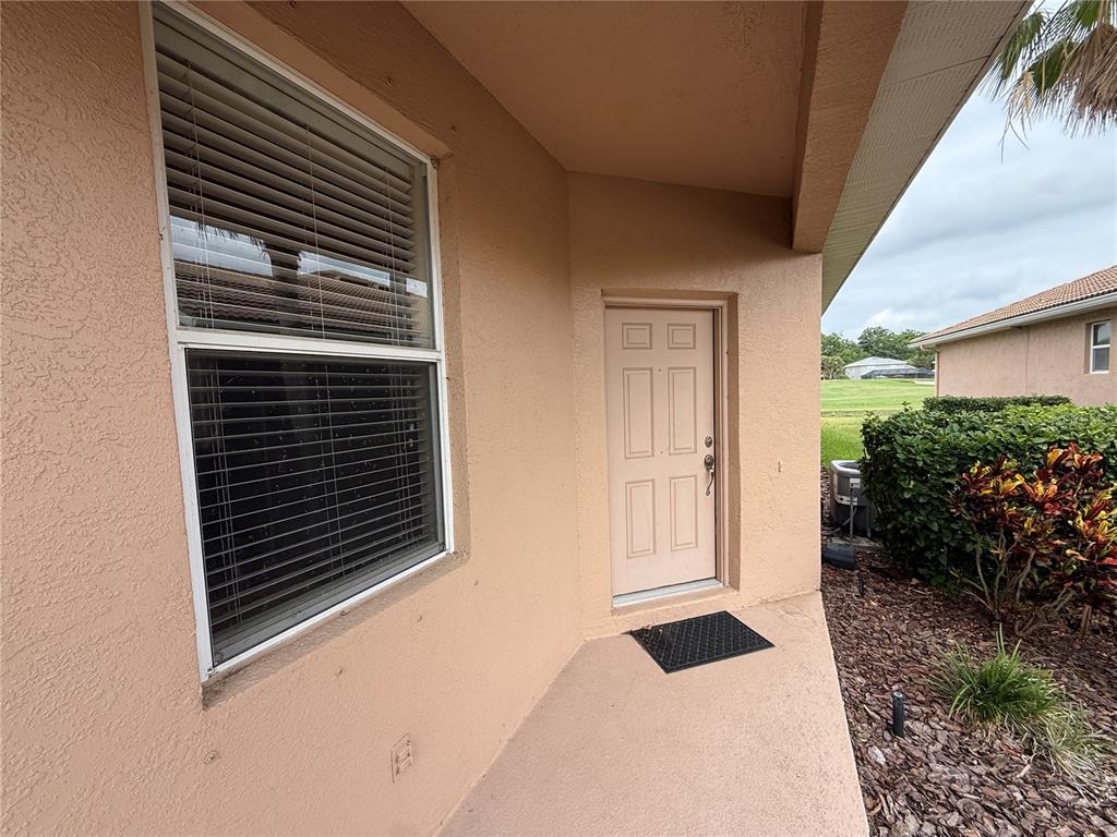 A beige exterior wall features a window with blinds and a single entry door — 342 FAIRWAY ISLES LANE, BRADENTON, FL
