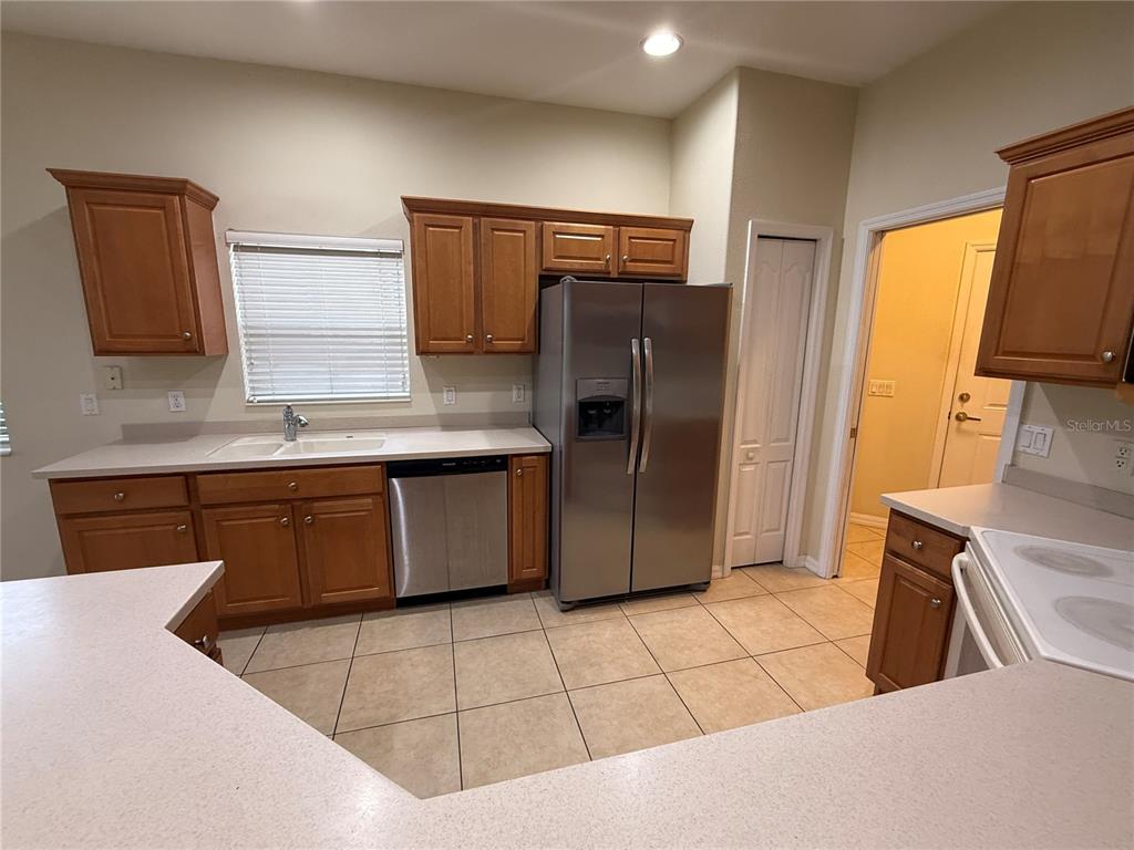 A kitchen features wood cabinets, stainless steel appliances, tile flooring, and a white countertop — 342 FAIRWAY ISLES LANE, BRADENTON, FL