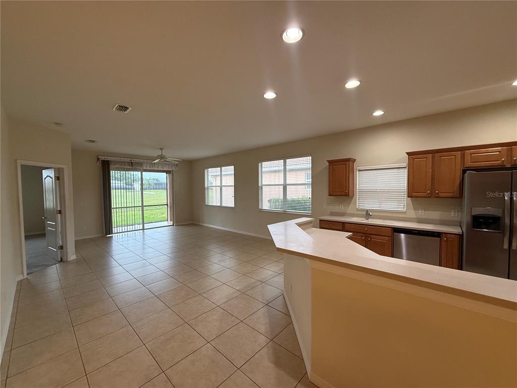 A kitchen with wood cabinets and stainless steel appliances overlooks an open-concept living area — 342 FAIRWAY ISLES LANE, BRADENTON, FL