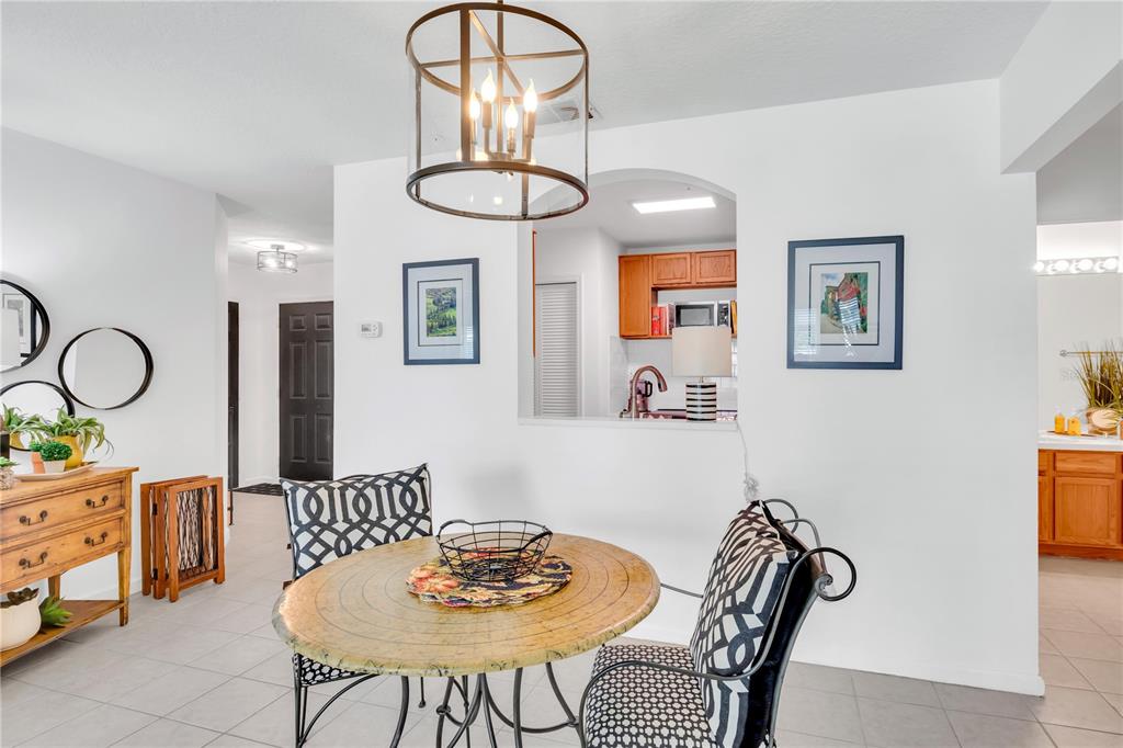 A dining area with a round table, patterned chairs, and a view into the kitchen — 3950 SOUTHPOINTE DRIVE UNIT 409, ORLANDO, FL