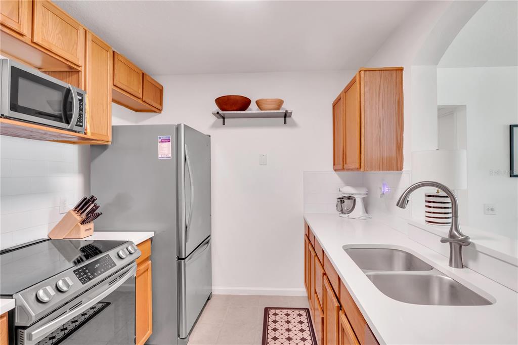 A kitchen features wooden cabinets, stainless steel appliances, white countertops, and a double sink — 3950 SOUTHPOINTE DRIVE UNIT 409, ORLANDO, FL