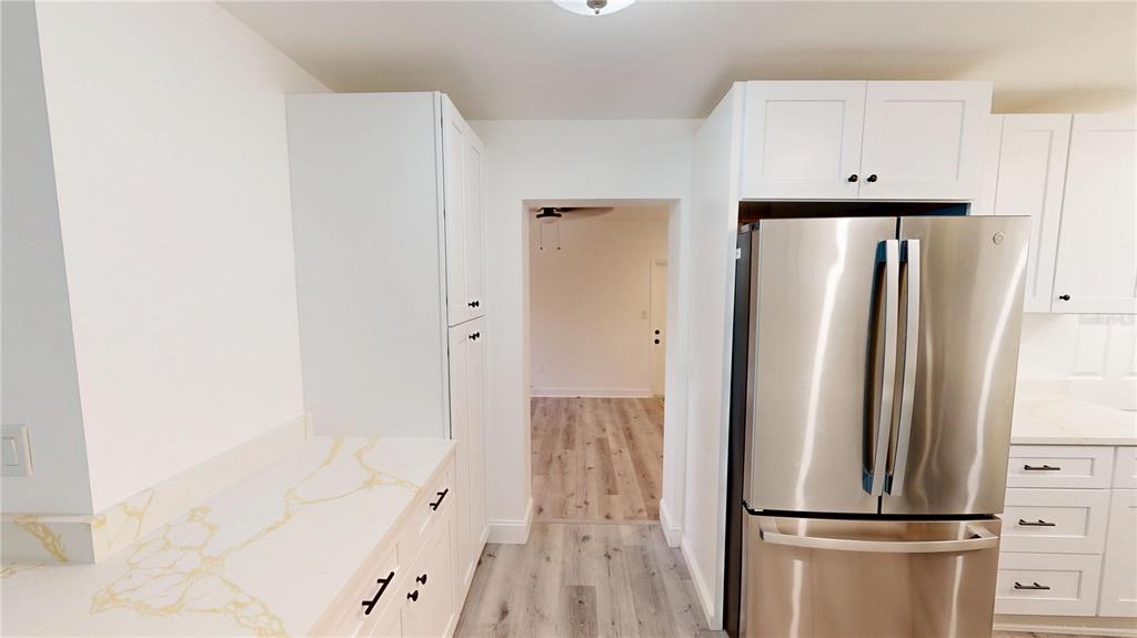 A kitchen features white cabinets, a stainless steel refrigerator, and a marble-patterned countertop — 4421 GANDY CIRCLE, TAMPA, FL