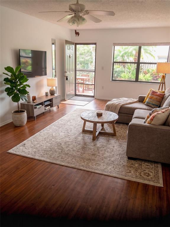 A living room features wood-look flooring, a gray sectional sofa, and a glass-paneled entry door — 305 30TH AVENUE W UNIT A207, BRADENTON, FL