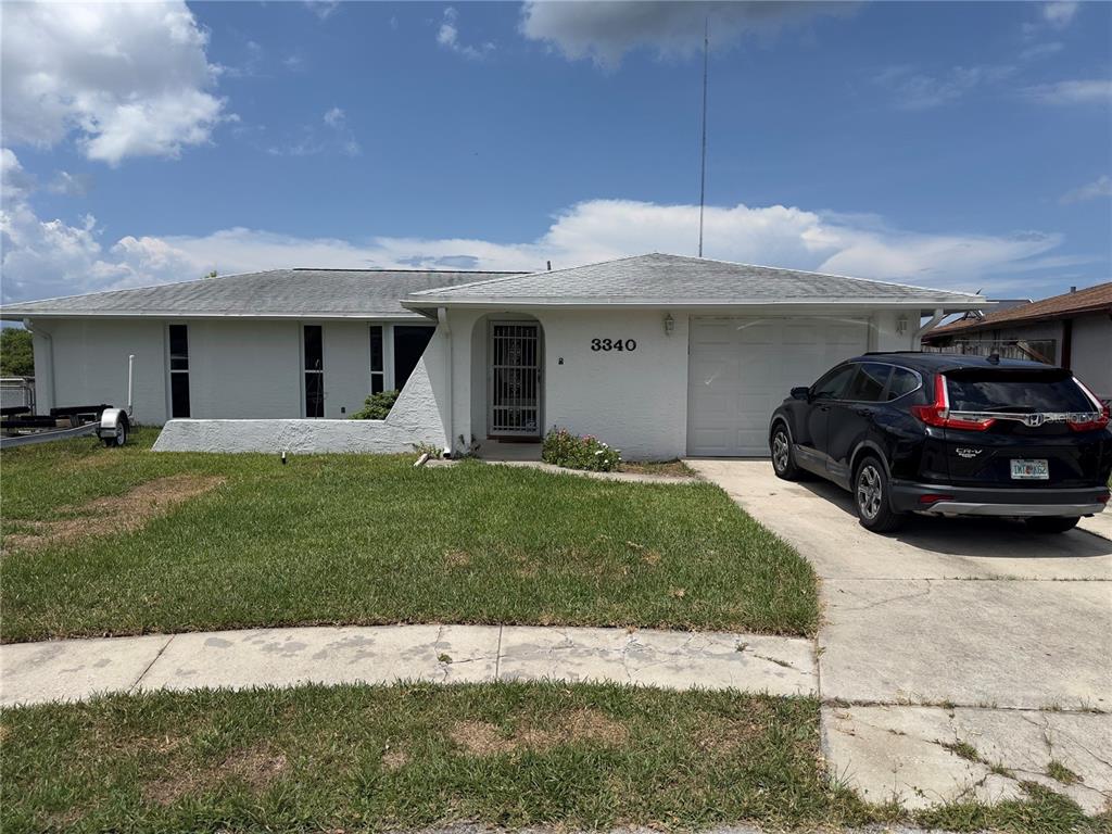 A single-story white house with a garage and a black SUV in the driveway — 3340 WILSON DRIVE, HOLIDAY, FL