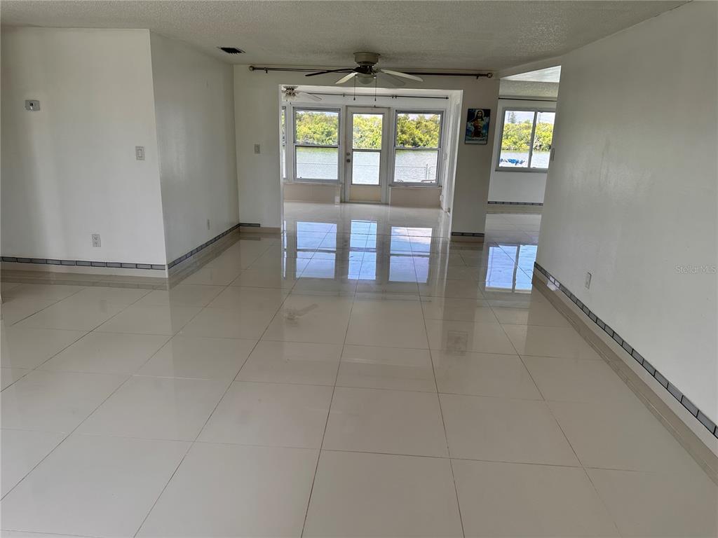 A bright living area features white tile floors, a ceiling fan, and water views — 3340 WILSON DRIVE, HOLIDAY, FL