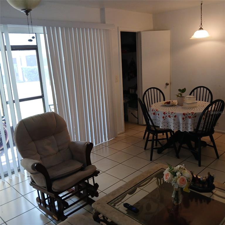 A dining area with a round table, chairs, and a rocking chair on tiled floors — 8609 N CHAMPLAIN COURT UNIT 77, TAMPA, FL
