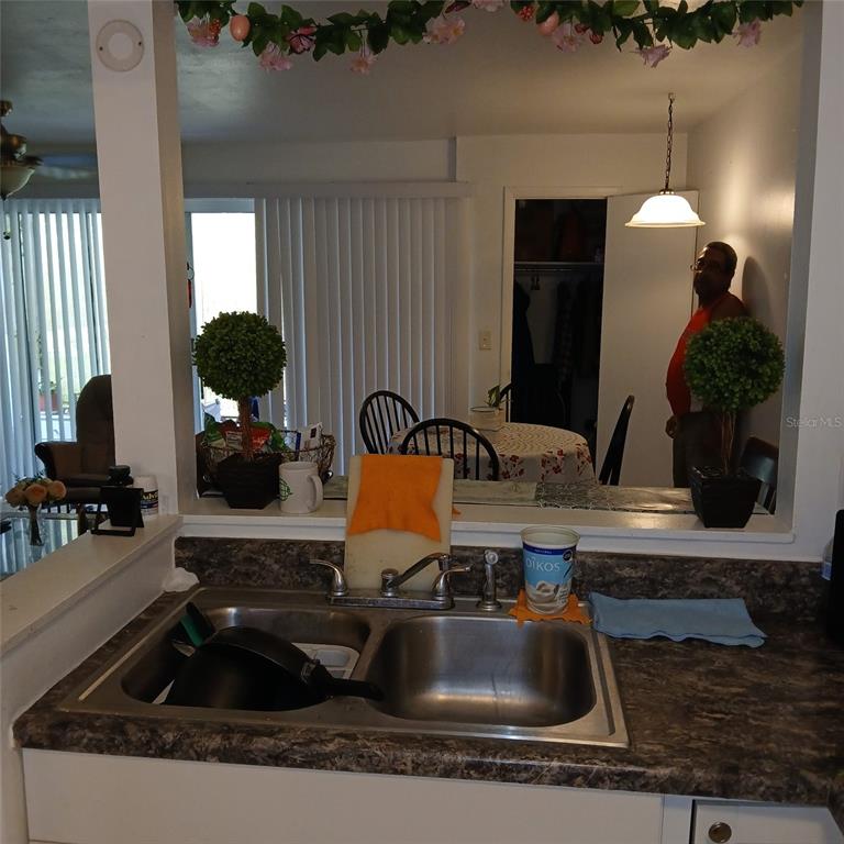 A kitchen sink with a laminate countertop overlooks a dining area with a mirror — 8609 N CHAMPLAIN COURT UNIT 77, TAMPA, FL