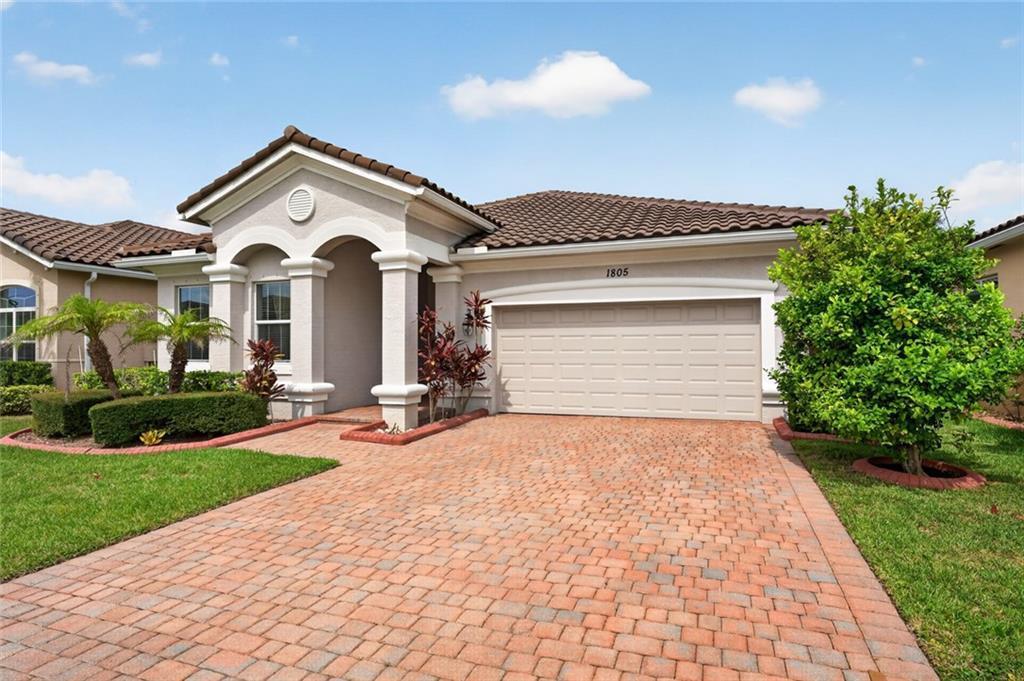 A single-story house with a brick paver driveway, a two-car garage, and a tiled roof — VERO BEACH, FL