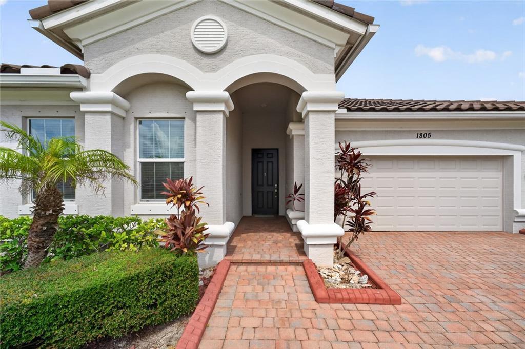 The exterior of a house features a brick walkway, a covered entryway, and a garage — VERO BEACH, FL