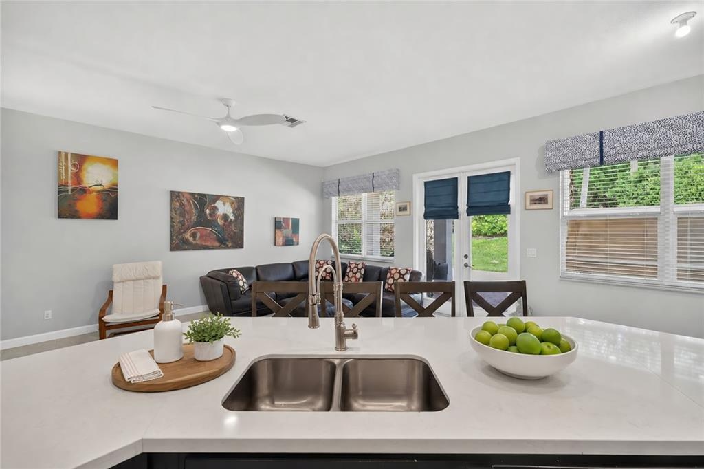 A kitchen island with a double sink overlooks a living area with a sectional sofa — VERO BEACH, FL